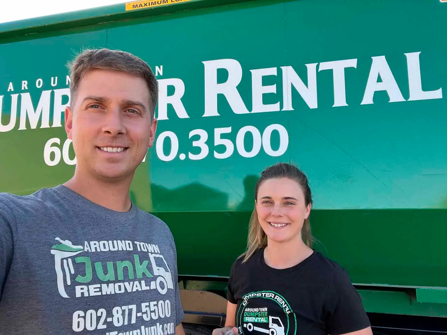 Two Around Town team members in front of a branded green dumpster