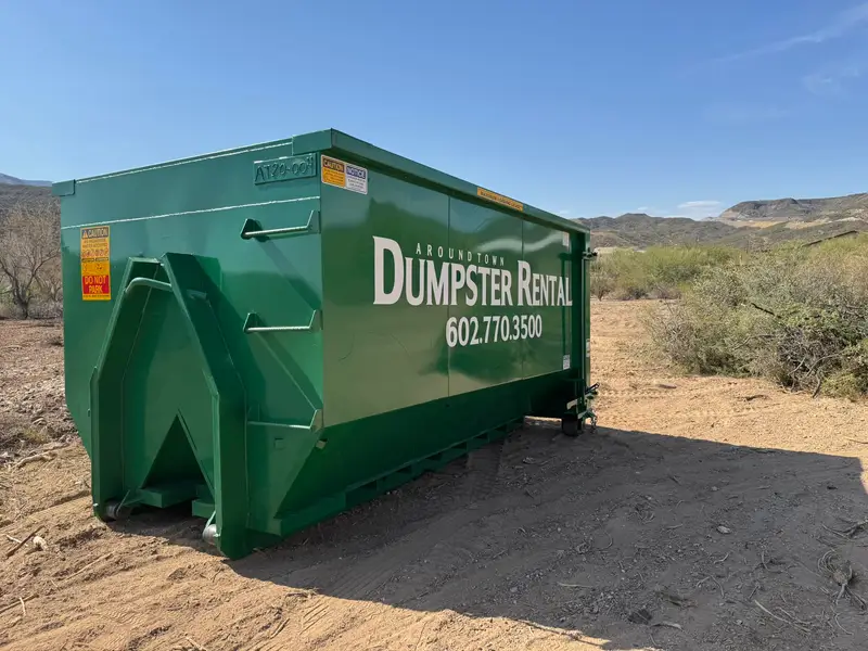 Green roll-off dumpster on a desert job site